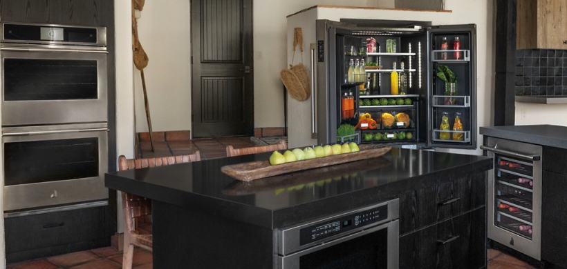 A modern kitchen with black marble counter and backsplash.